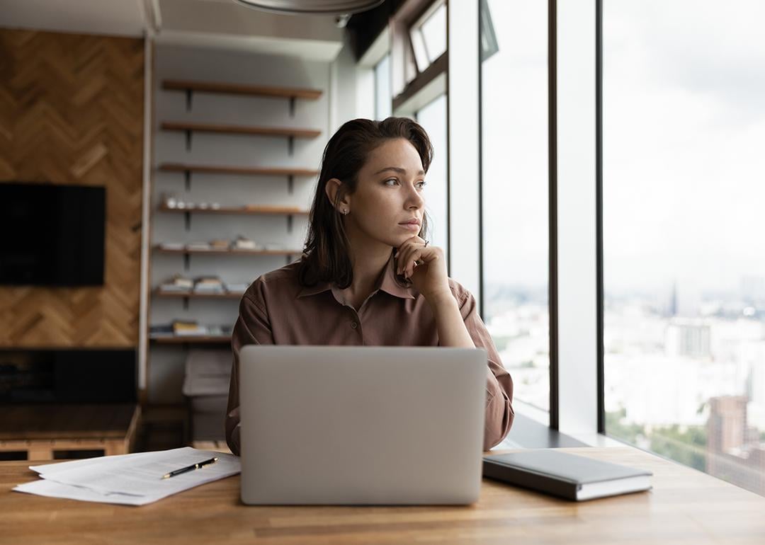 A young businesswoman in an office looking out the window.