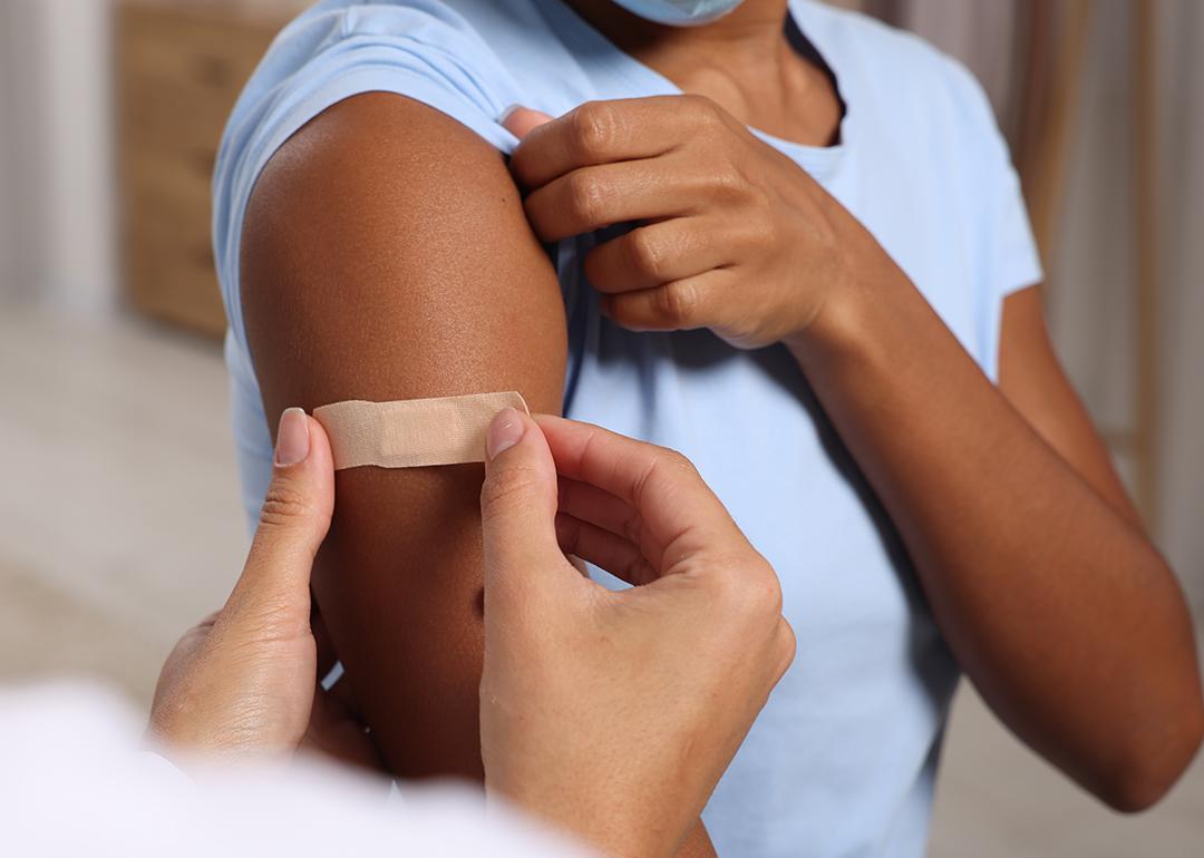 A doctor puts adhesive bandage on a woman's arm after vaccination.