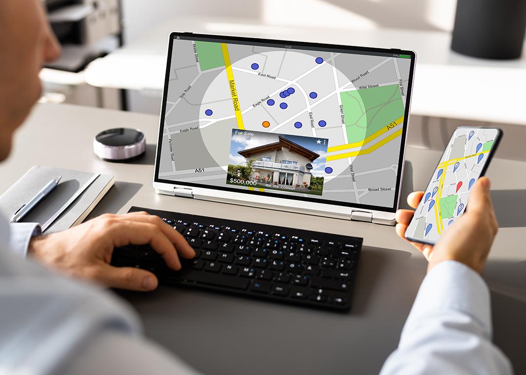 Person looking up a map view of a property's location using a laptop and a phone.