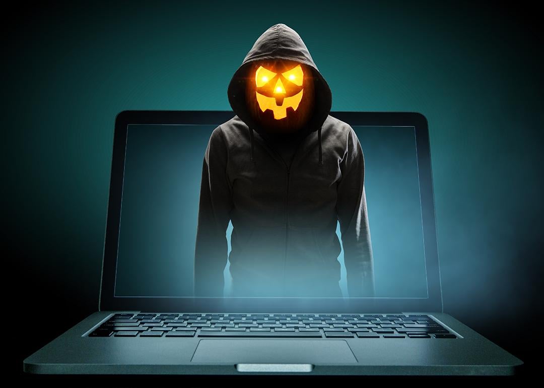 Anonymous man with a Halloween pumpkin head illustrated as emerging from a laptop.