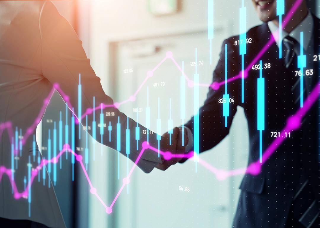 Stock chart graphics over business people shaking hands.