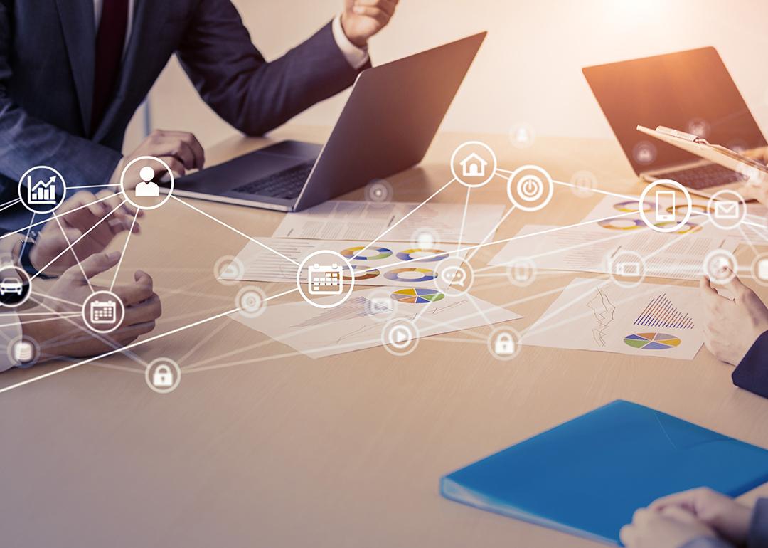 Business people in a meeting with an overlay of networking and communication icons.