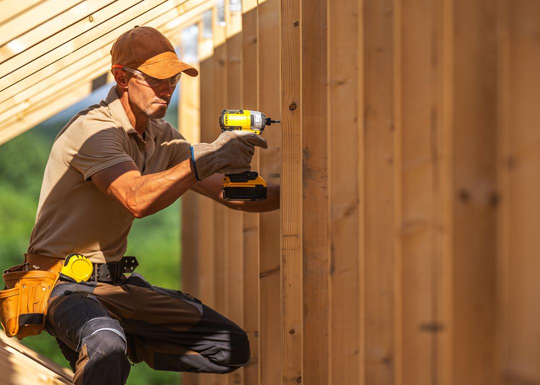 A skilled carpenter securing wooden panels using an electric power drill.