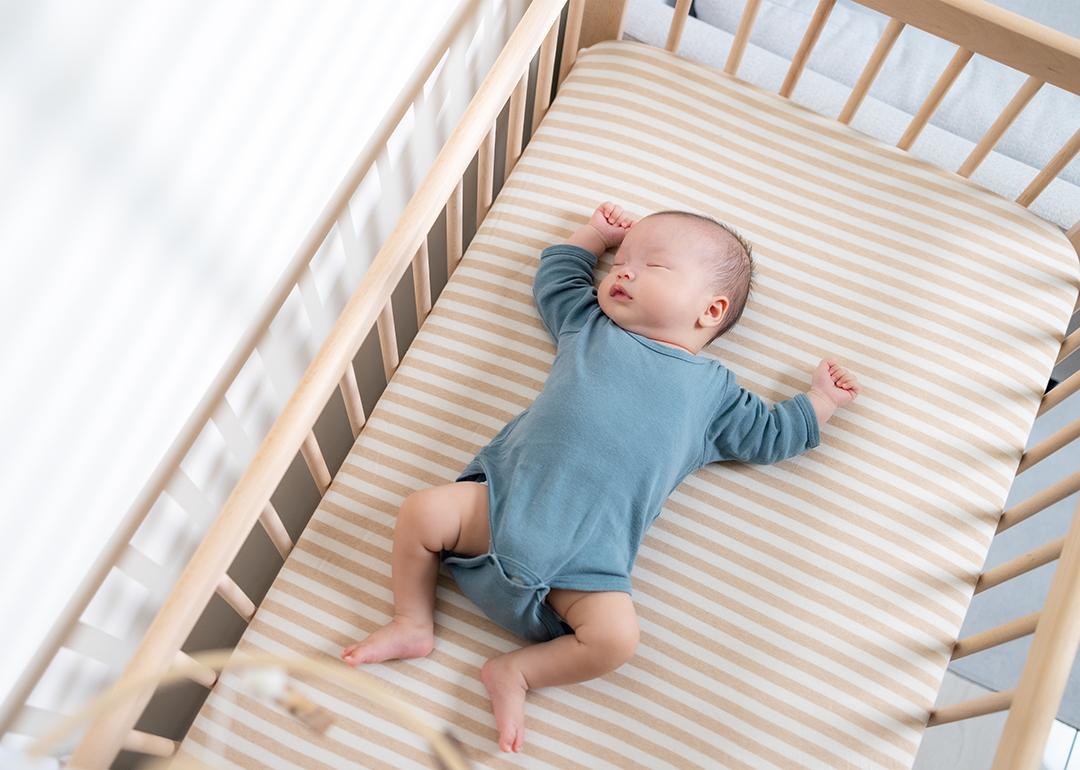 An infant quietly sleeps in a crib.