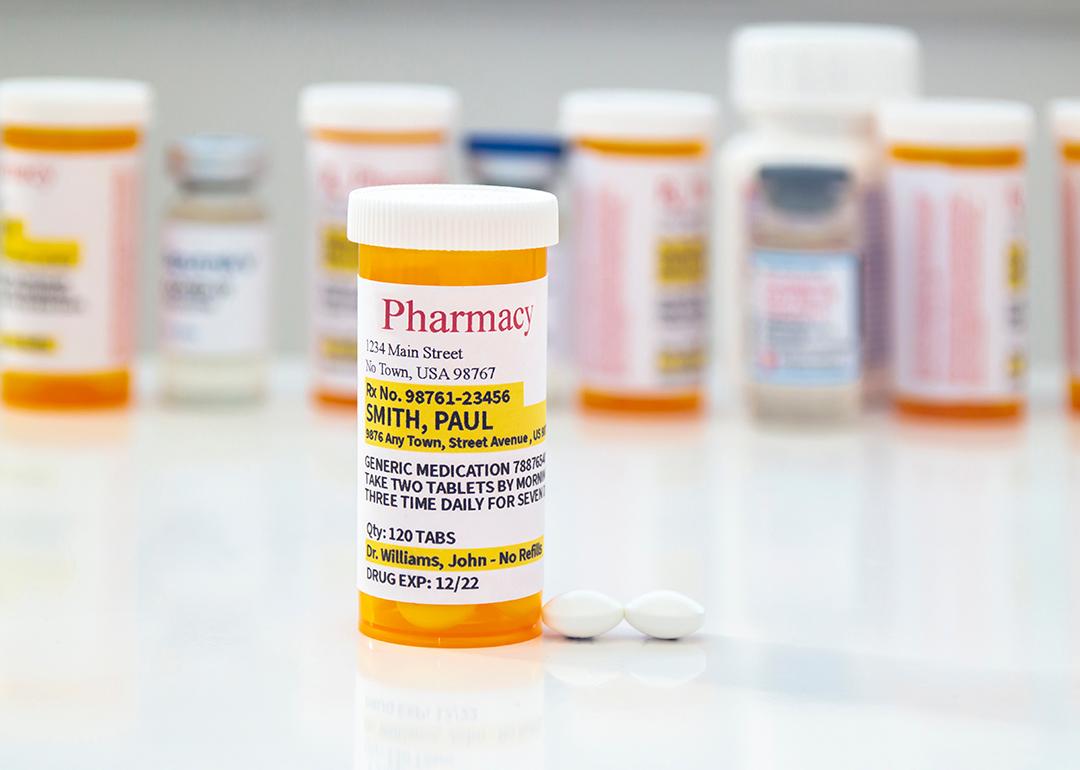 A generic prescription medicine pill bottle in front of a row of other pill bottles.