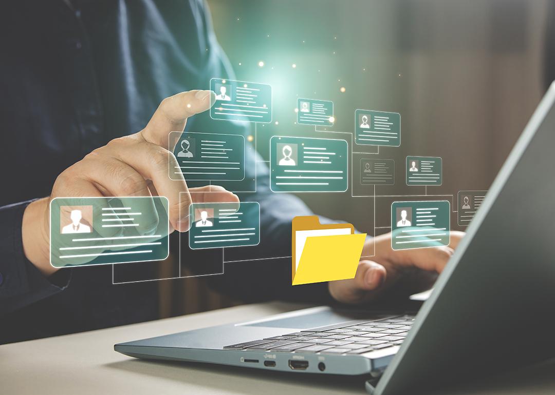 Businessperson using a laptop hovers at graphic illustration of a personal file management software.