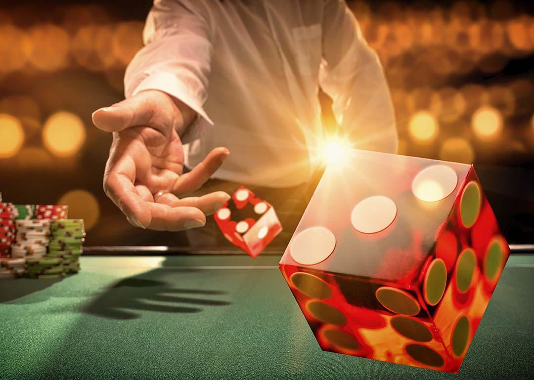 Man throws die at a casino table.