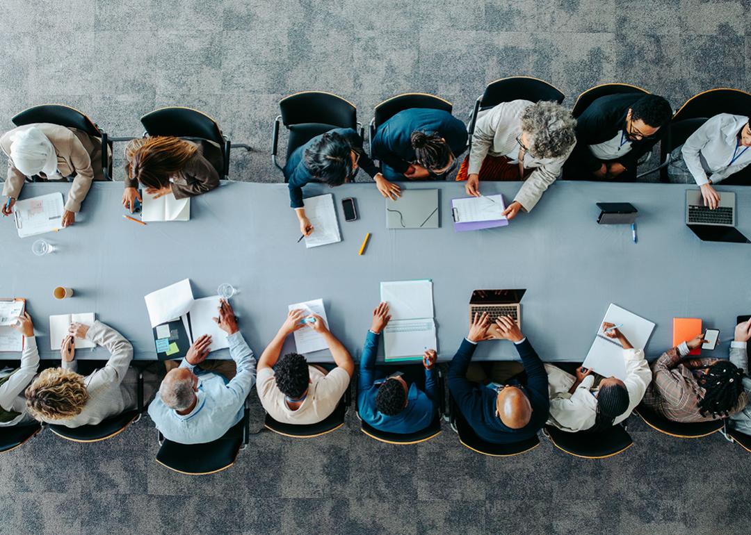 Top view of a large business group around a table during a meeting.