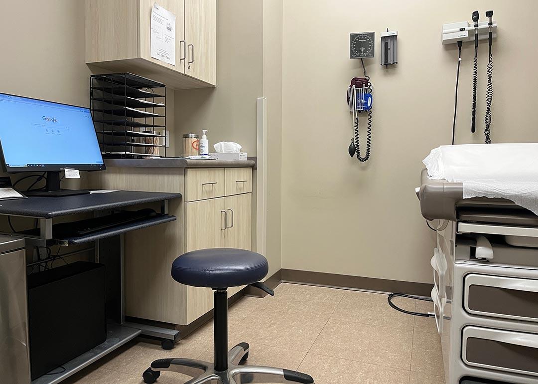 An empty examination room in a clinic with a computer, exam tamble, stool and various medical devices on the wall in Muscle Shoals, Alabama USA.