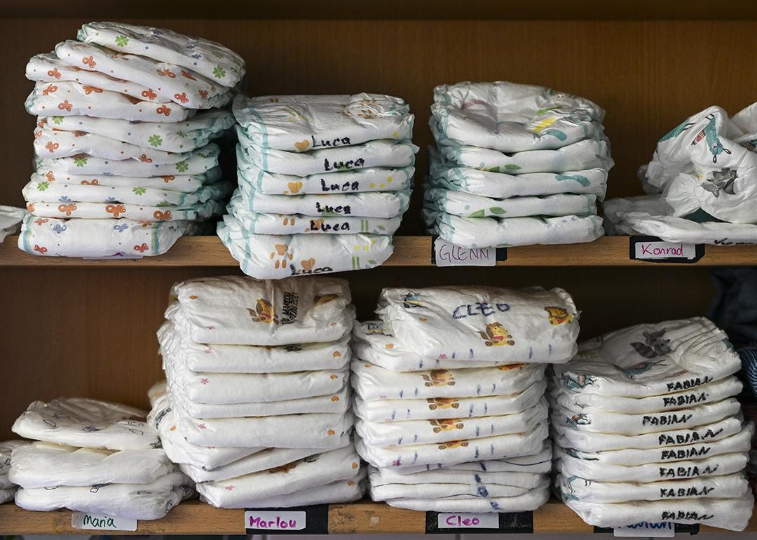 A daycare center's shelf with stacks of various children's diapers with their names written on them.