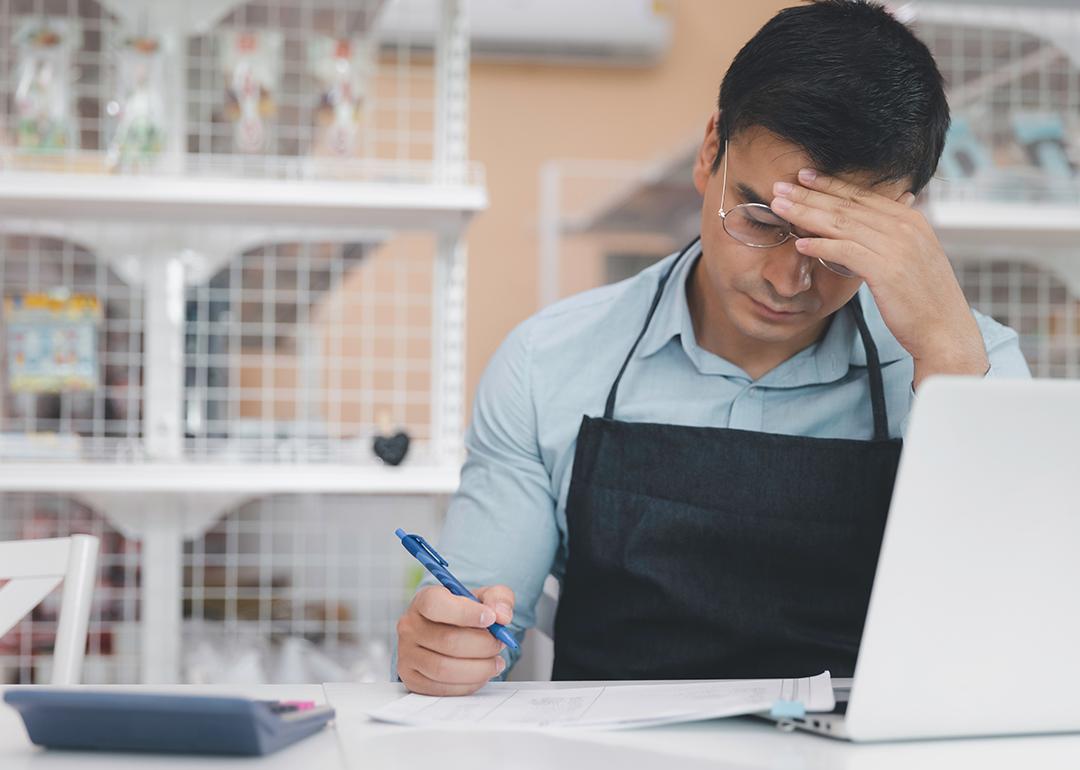 A male small business owner feeling stressful while reading finance documents.
