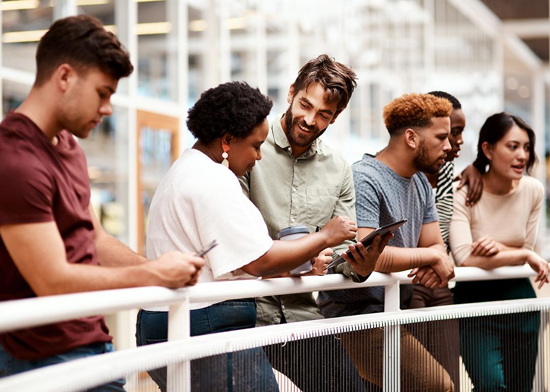 An office team engaged in discussion while standing by a railing.