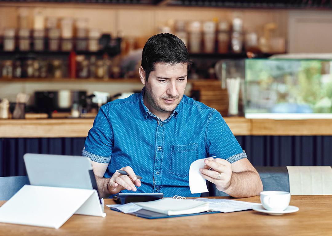 A male restaurant owner calculating business bills.