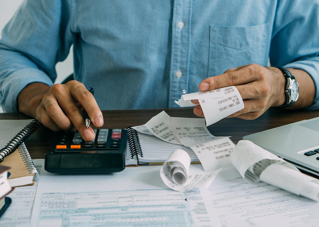 A man computes bills using a calculator.