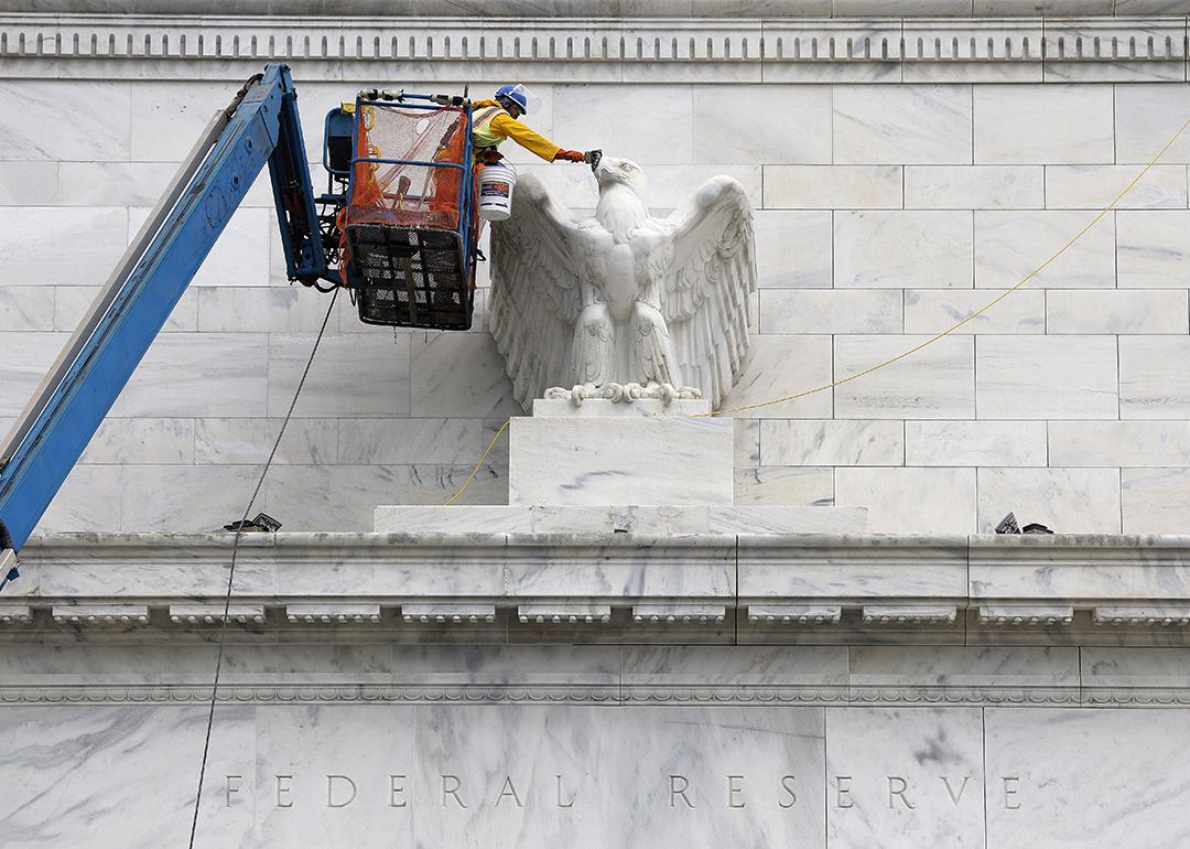 Workers paint an eagle statue on the Marriner S. Eccles Federal Reserve Board Building in Washington, DC.
