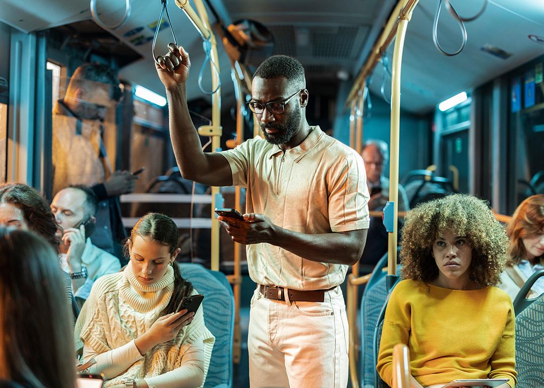 A young black man standing in a crowded bus at night.