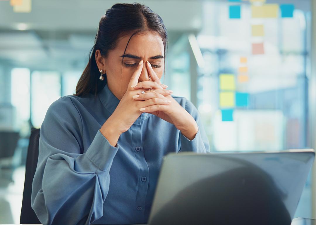A frustrated young woman in front of her laptop at work.