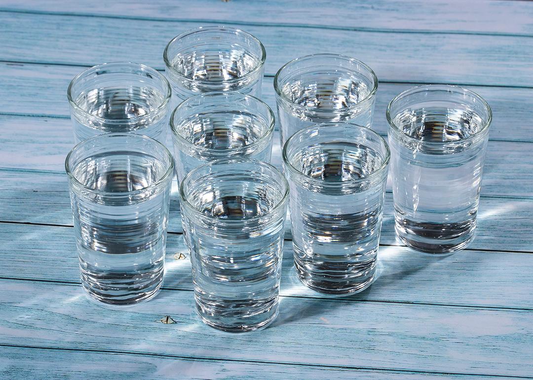Eight glasses of water on a wooden table.