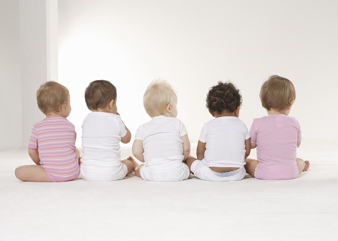 Rear view of five babies sitting on the floor.