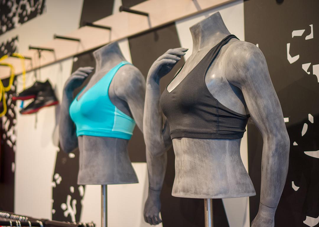 Different colors of women's sports bra displayed on torso mannequins at a sports clothing store.