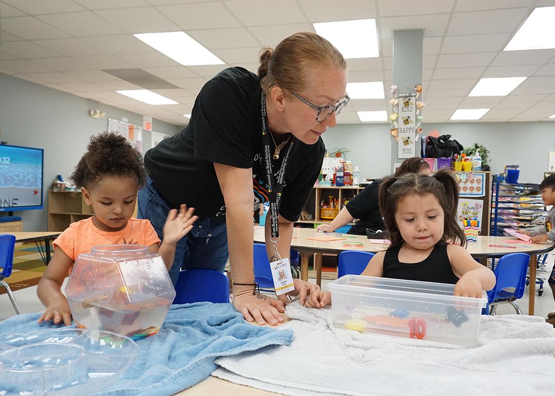 Head Start teacher Sasha Fair helps two preschool children with a science experiment.