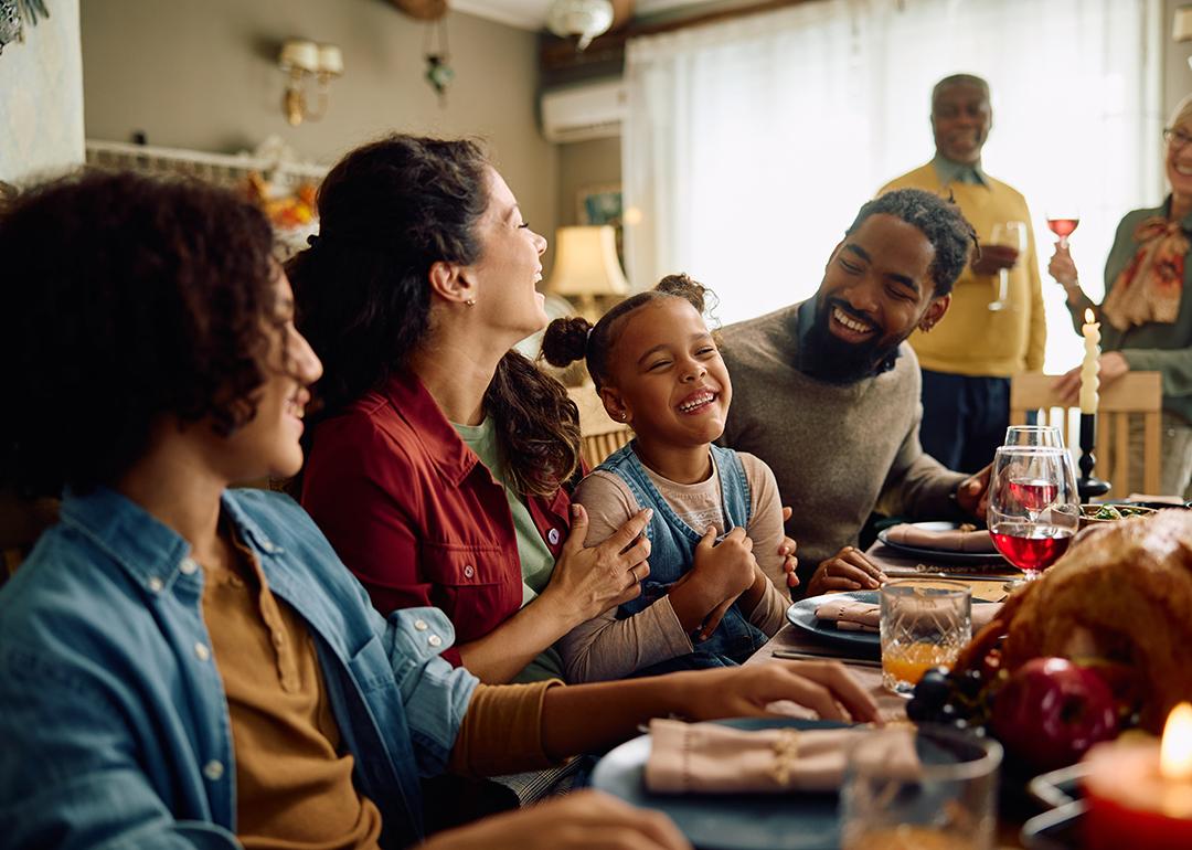 A big family laughing during Thanksgiving dinner at home.