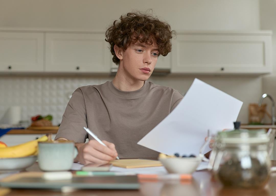 A young man reviewing a document during breakfast.