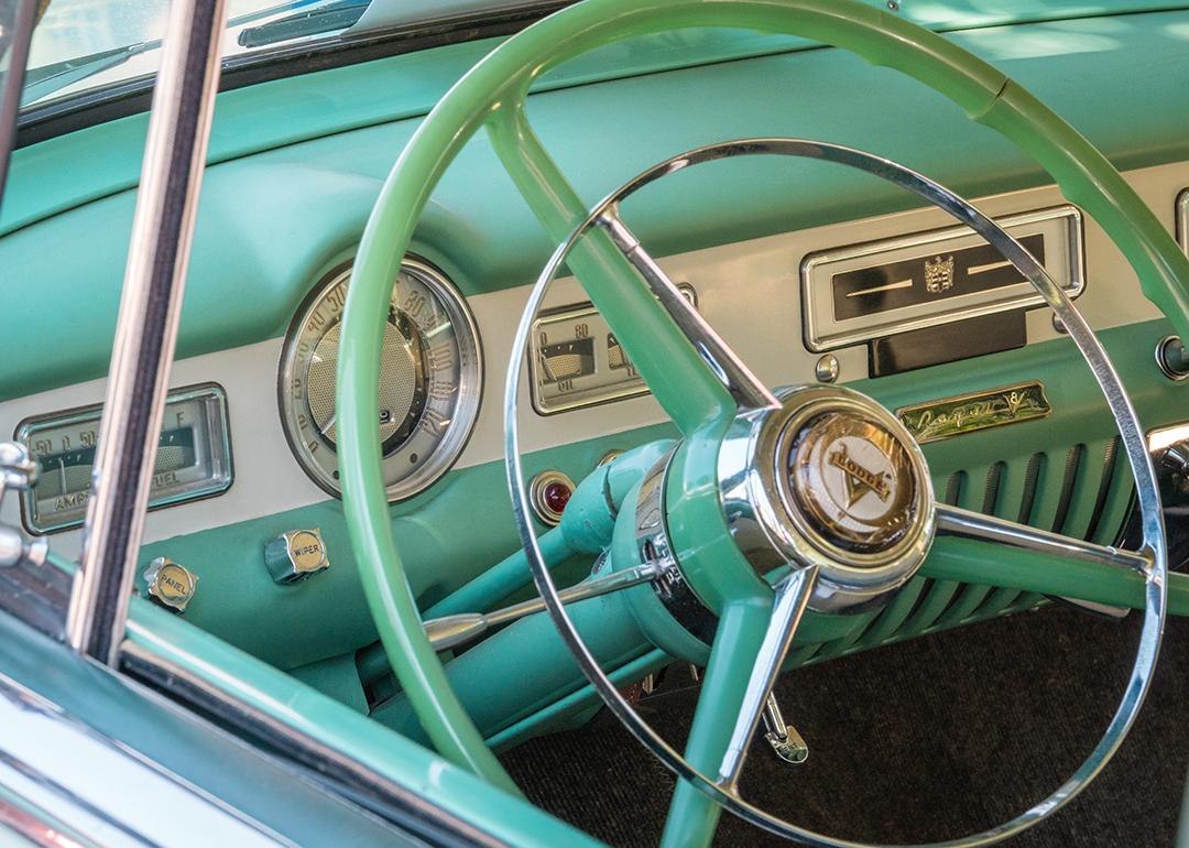 A close up view on a vintage pastel green car's steering wheel.