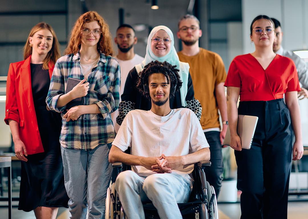 A diverse group of young business people, with a person in wheelchair at the center, showcasing community and accessibility.