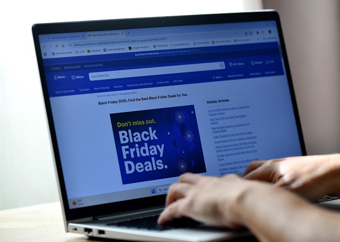 Hands typing on a laptop displaying a Black Friday Deals advertisement page.