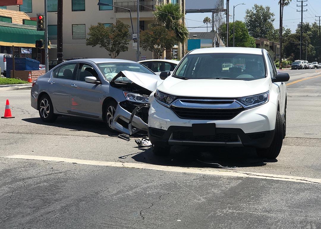 Two modern vehicles involved in a traffic accident are shown stopped in an intersection during the day in Los Angeles.