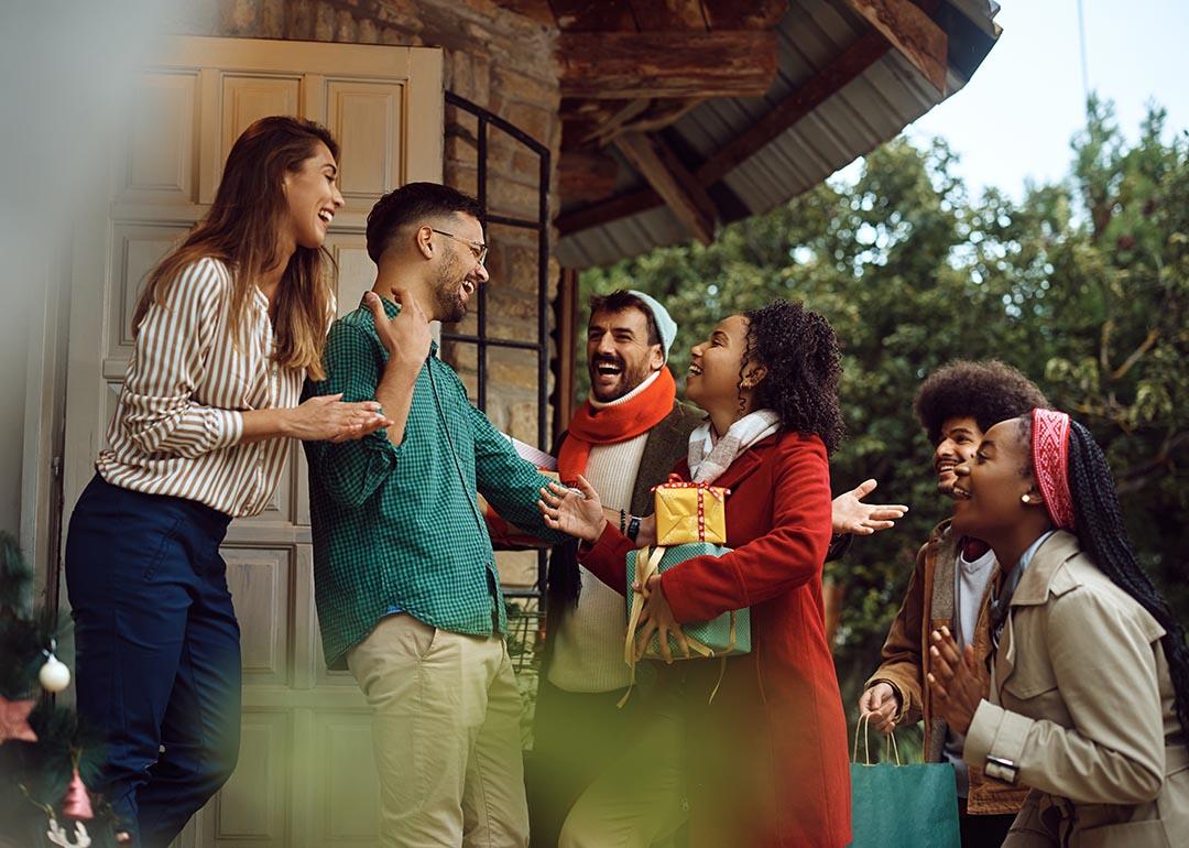 Young happy people greeting with a couple while arriving at their dinner party during winter holidays. 