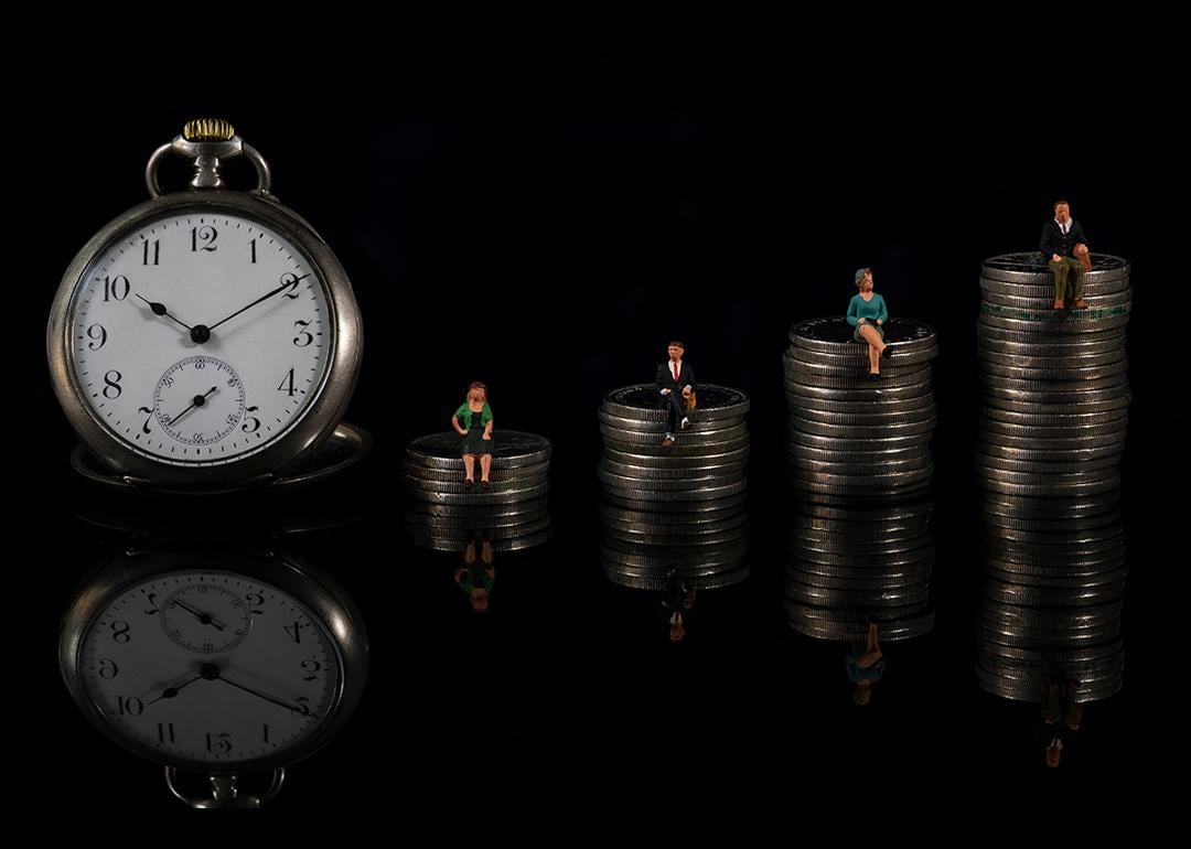 The concept of counting down to retirement illustrated by an increasing stack of coins with miniature people sitting on each one, with a clock placed on the side.