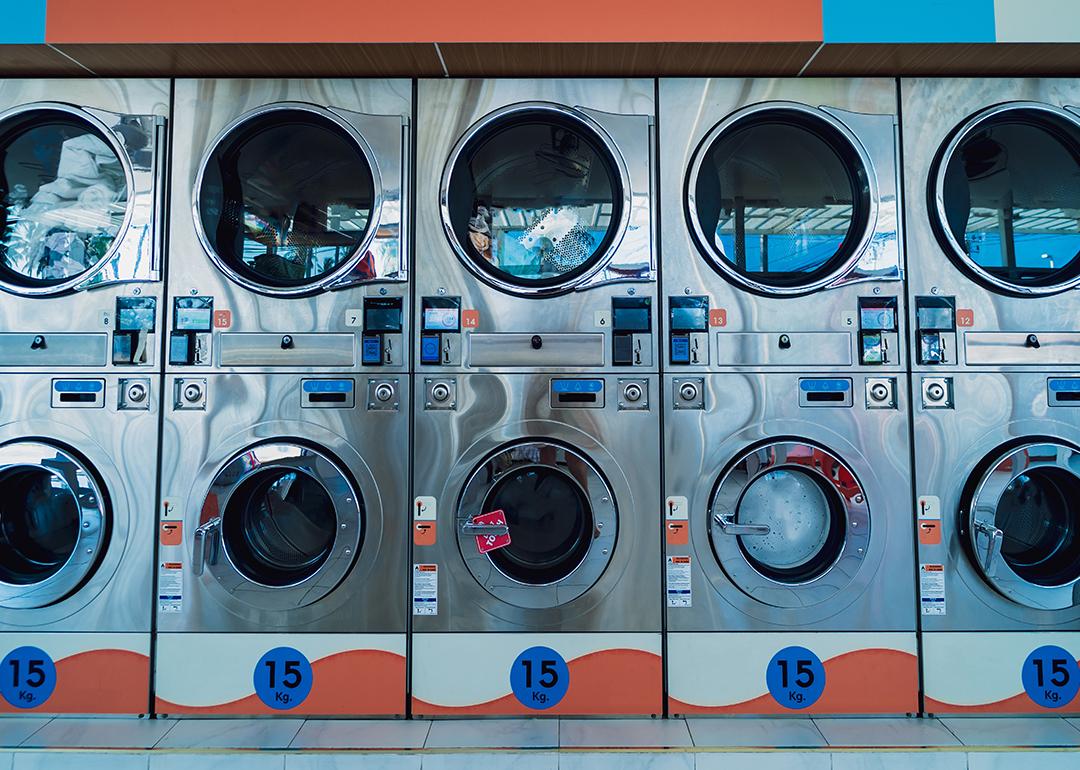 Rows of large industrial laundry machines in a laundromat.