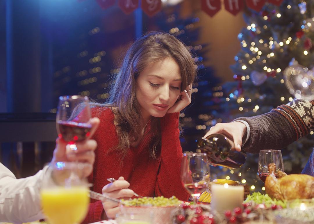 A young woman losing interest or appetite at a Christmas dinner table.
