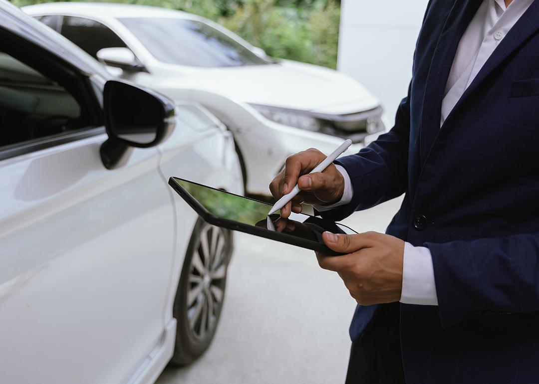 A car insurance agent inspects a damaged vehicle.