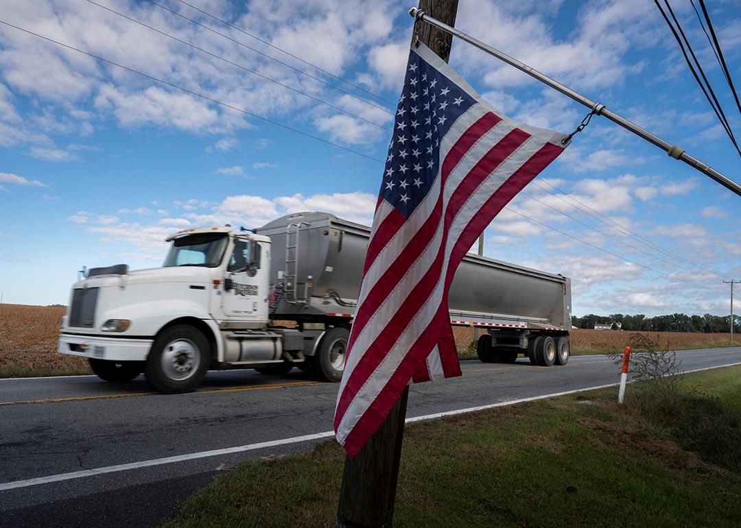 Travis Hutchison, a soybean farmer, drives his truck on a country road near his family's farm on a road behind an American Flag hanging, in Cordova, Maryland, on October 10, 2025.