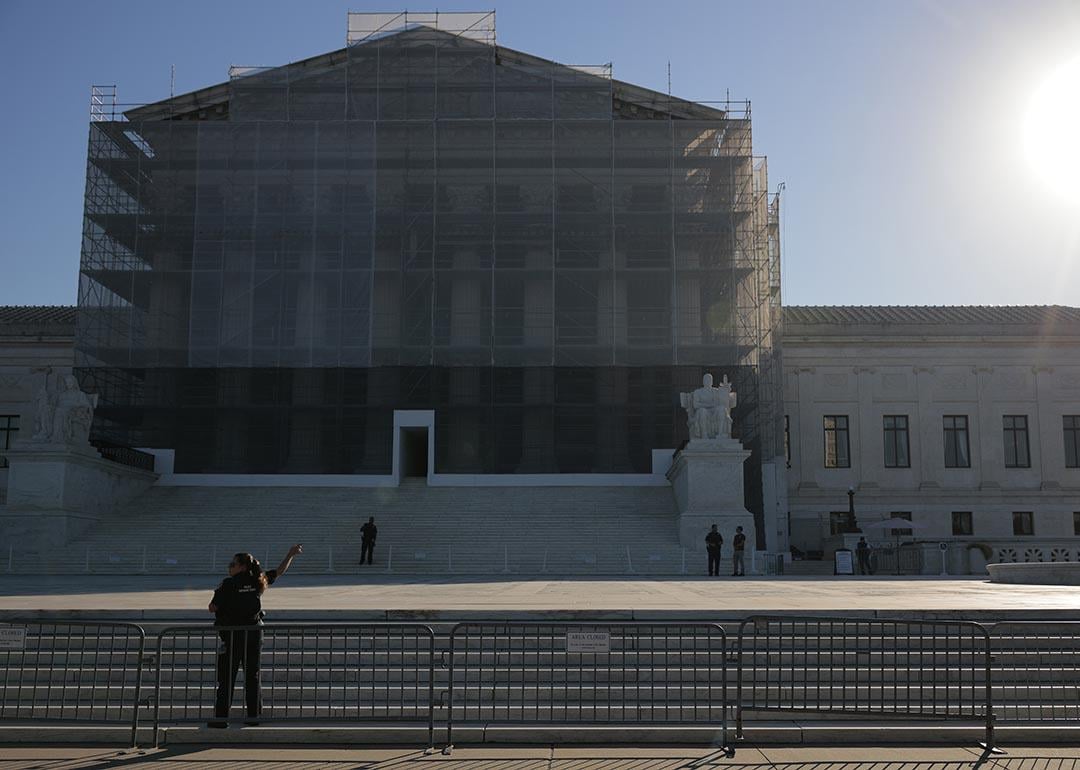 U.S. Supreme Court Police direct visitors from behind security barriers in front of court building, which is obscured in construction scaffolding, on the first day of the Court’s new term on October 06, 2025 in Washington, DC.  