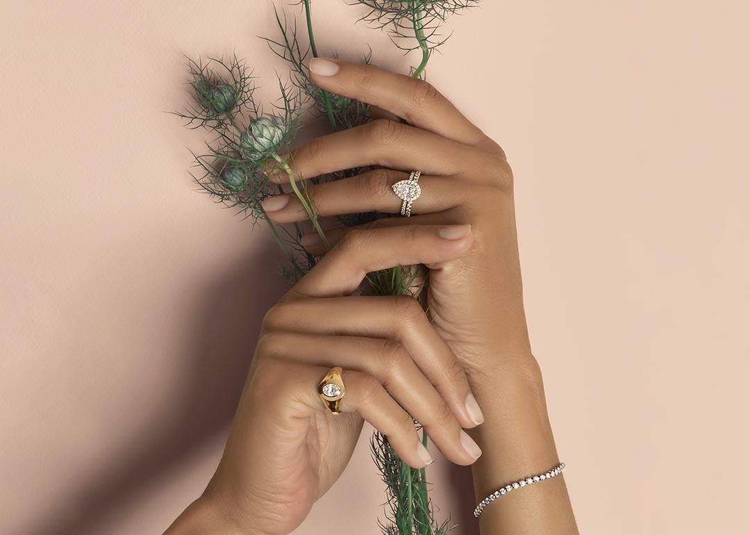 Hands of a bride holding flowers and showcasing diamond cut rings.