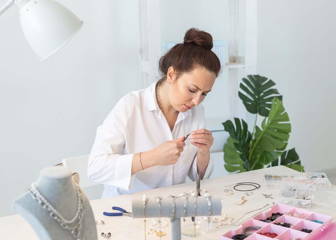A female professional jewelry designer working on hand-made jewelry in her workshop.