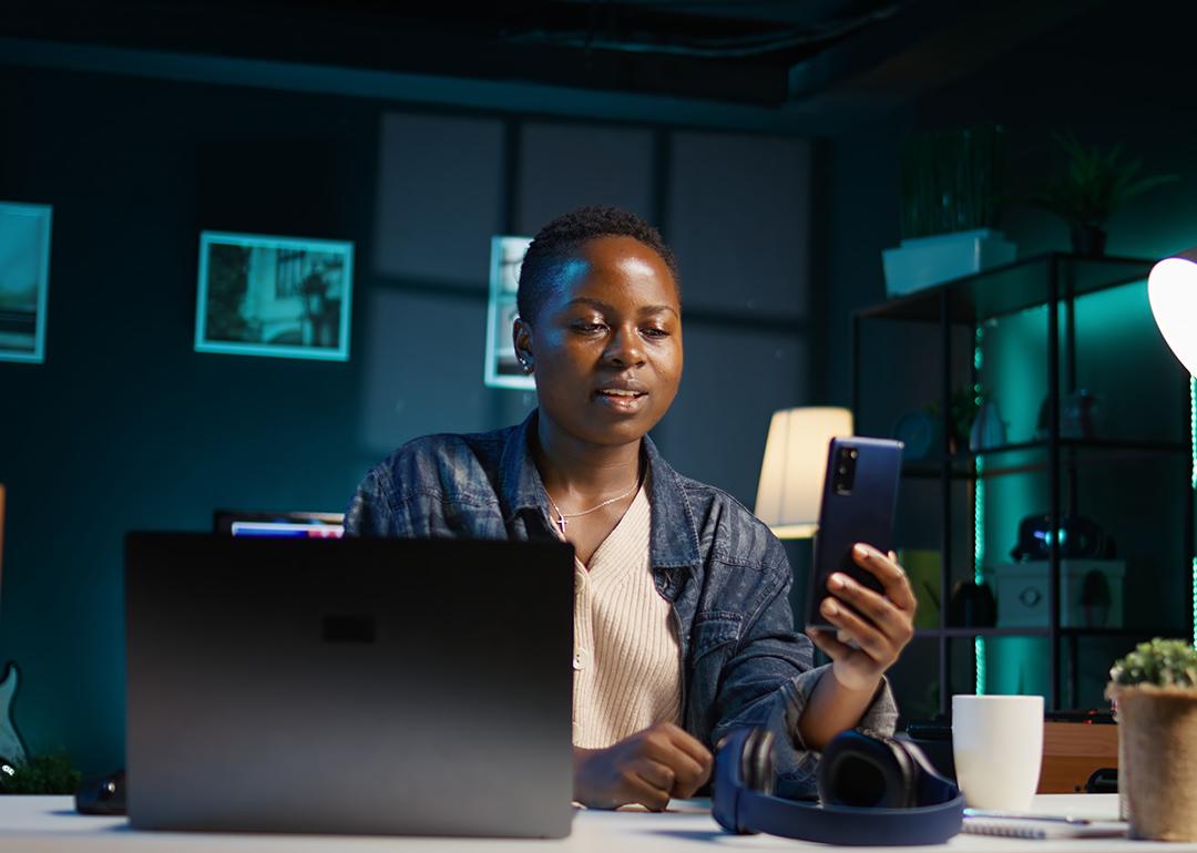 A black female professional answering a video call on her phone while working from home.