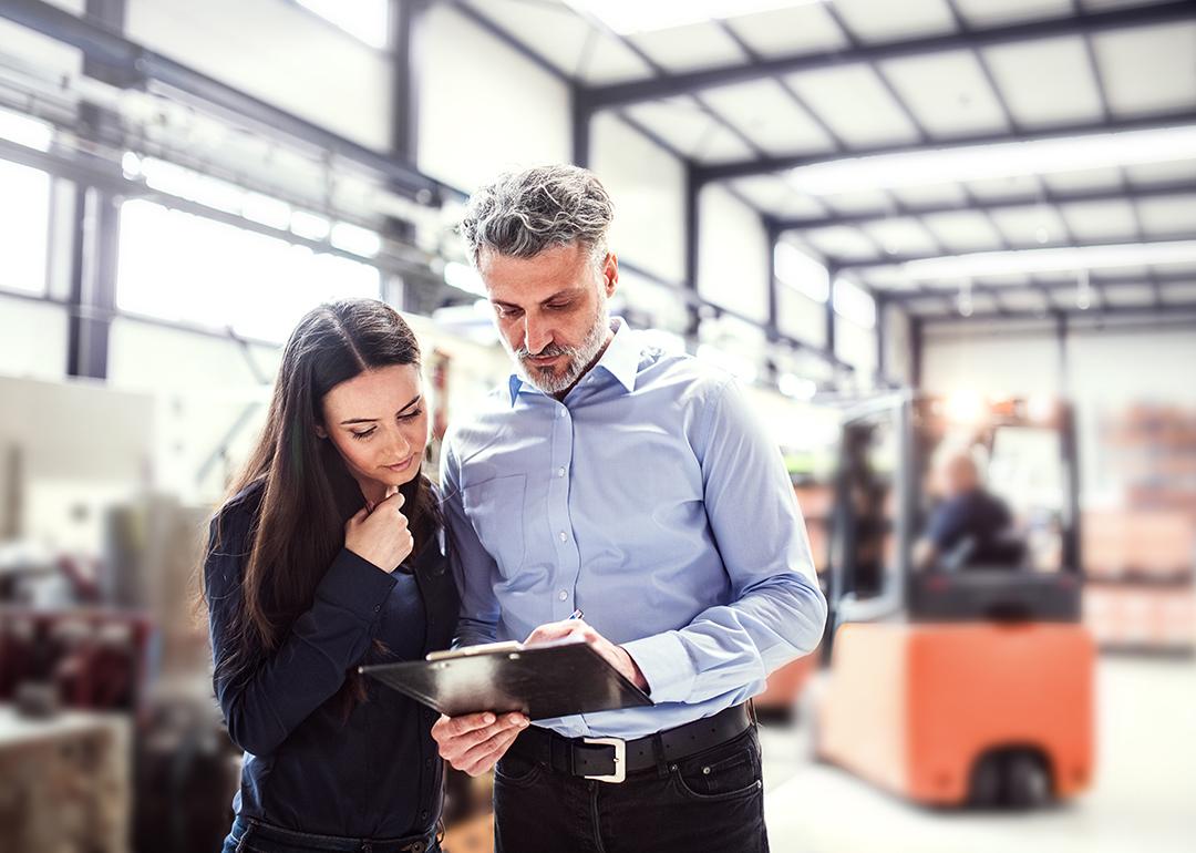 Warehouse manager and employee planning transport process in warehouse.