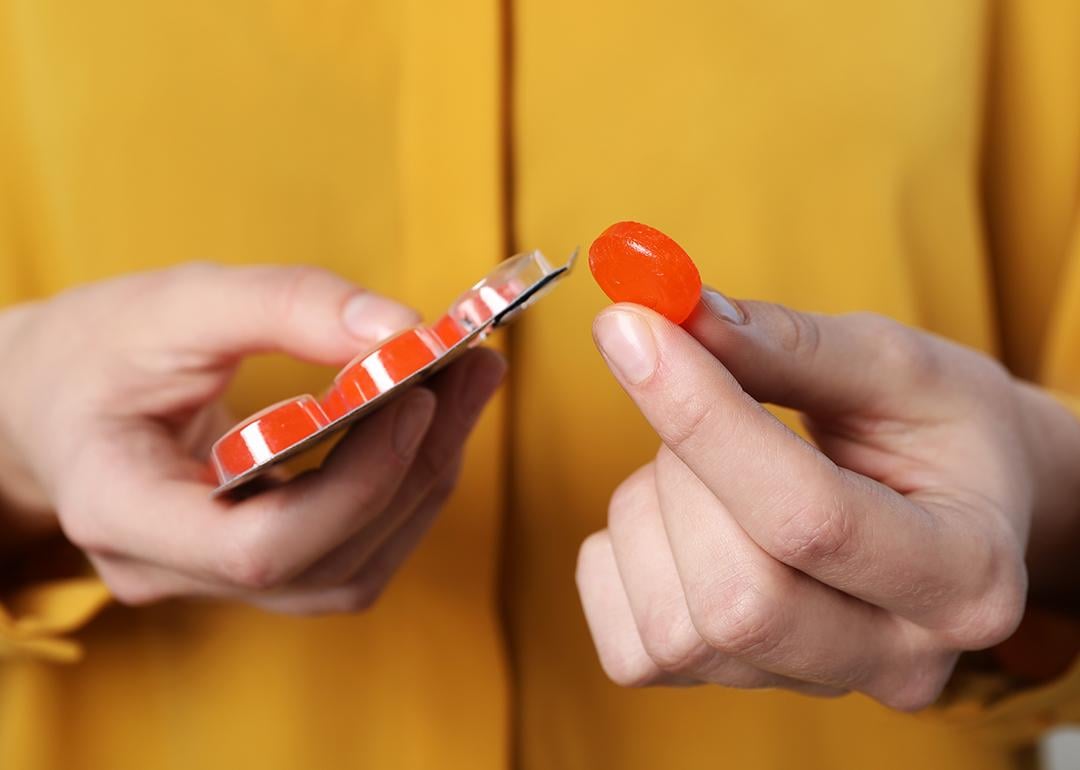 A woman holding a red cough drop tablet.