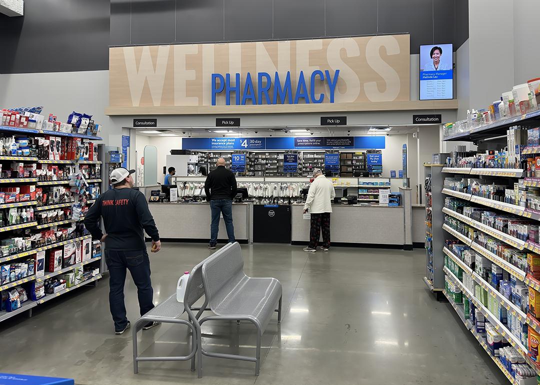 Customers picking up items at a pharmacy counter.
