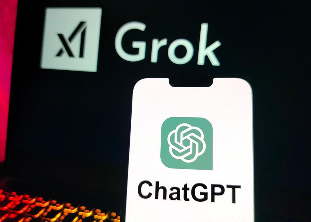 A smartphone displaying the ChatGPT logo and a laptop screen displaying X's Grok logo in the background.