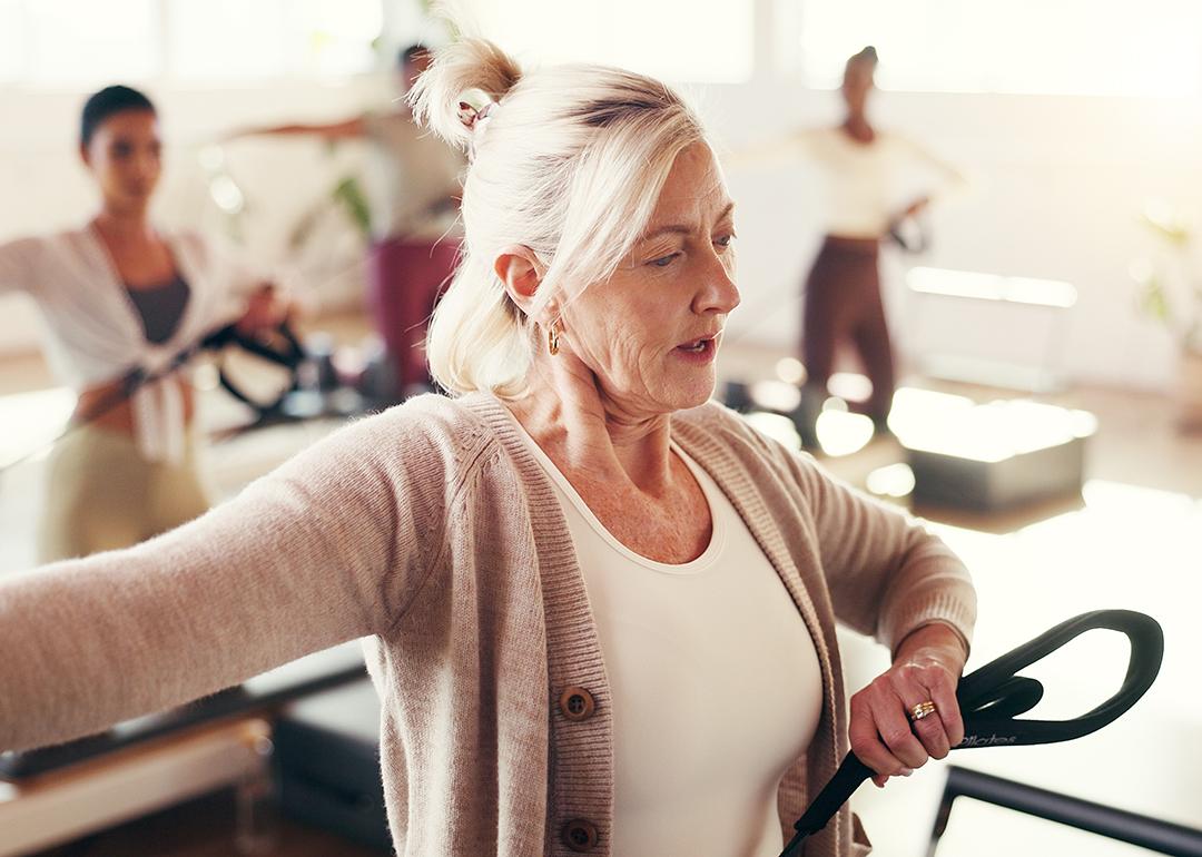 A mature female fitness coach leading a pilates class.