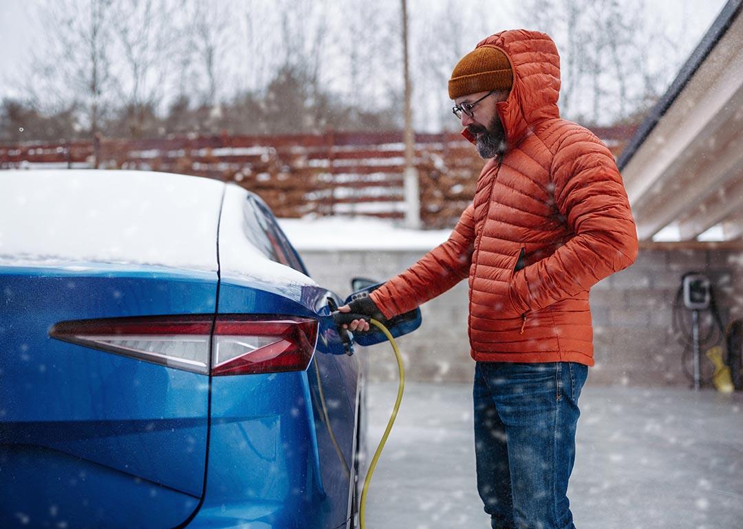 A man charging his EV during a snowy day.
