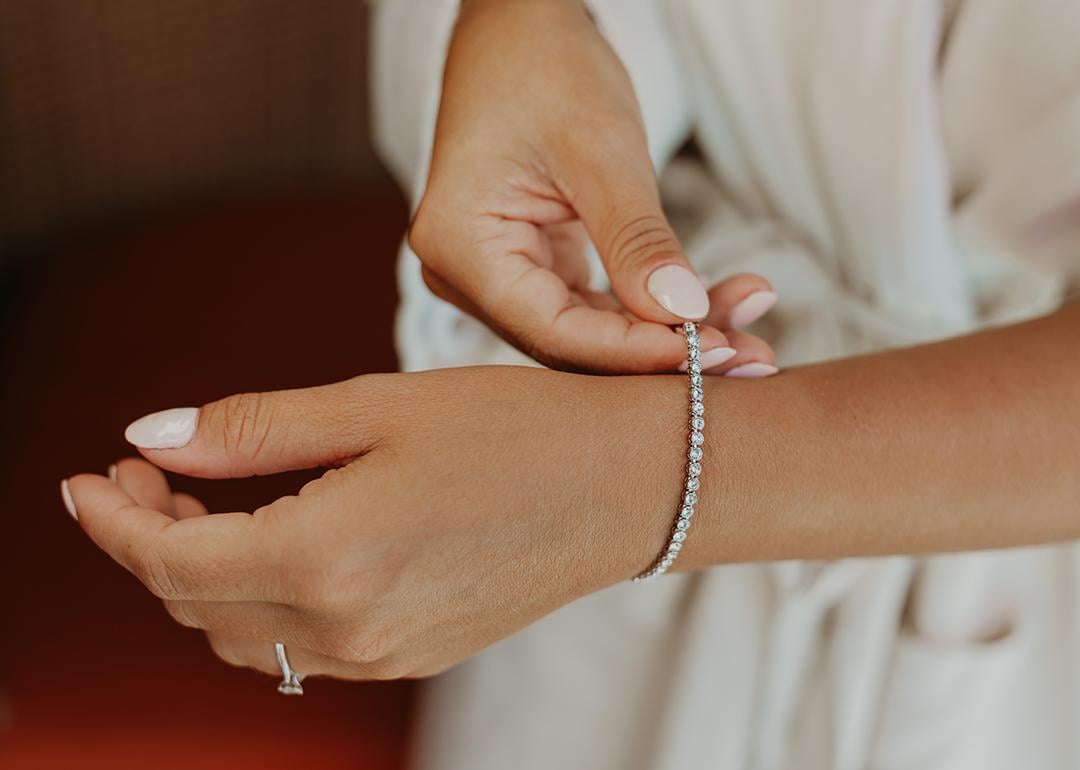 A bride putting on an elegant bracelet on her left wrist.