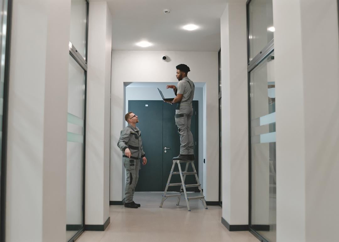 Two installation workers setting up a surveillance camera.