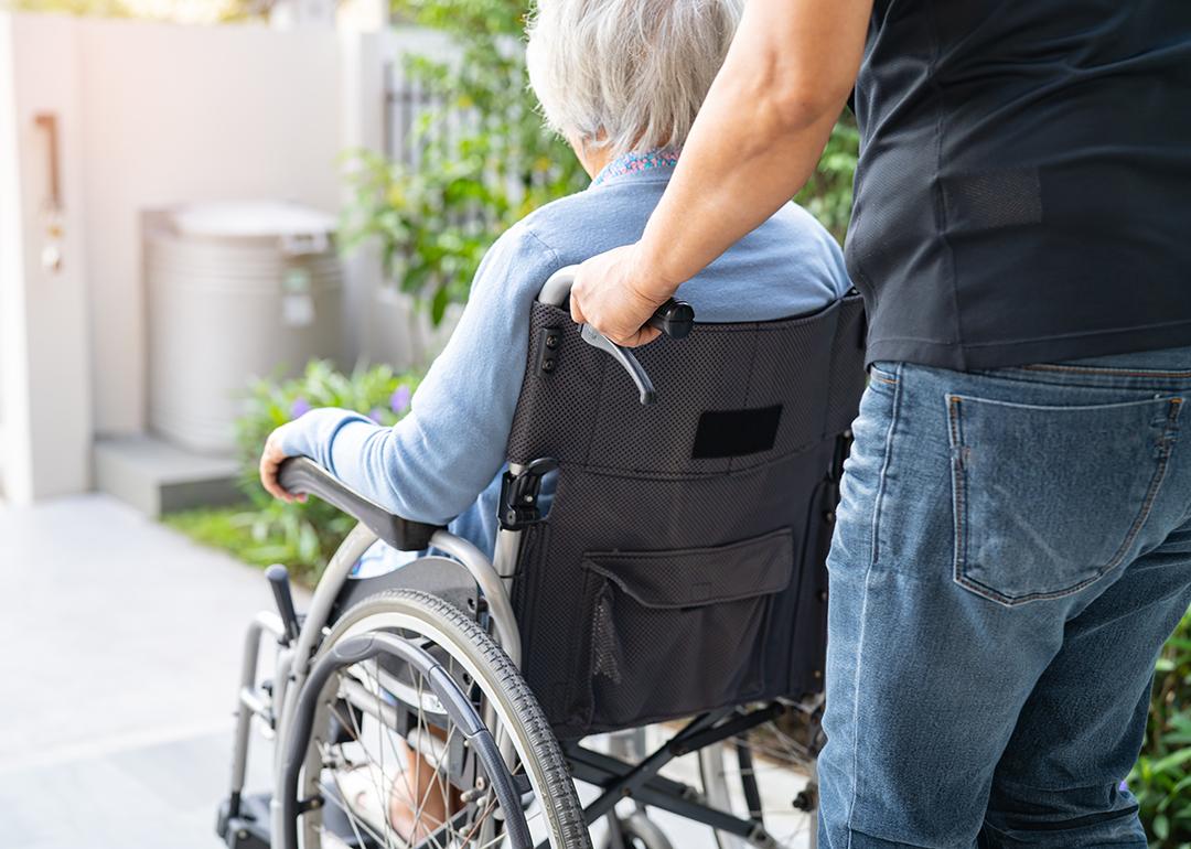 A caregiver caring for an elderly woman in a wheelchair.